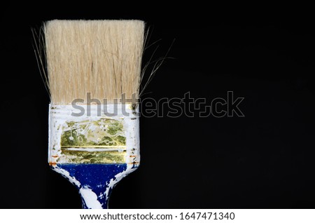 Used paint brush. Blue brush with a red tip in white paint. Macro photo. Repair brush in hand. Fibers Copy Space