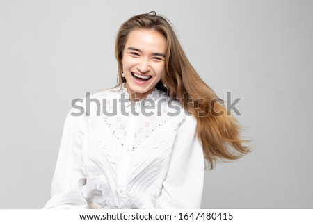 Very emotional woman laughs while tearing her stomach. Portrait of a beautiful woman on a white-gray background