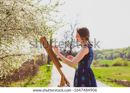 Artist paints a picture of blooming cherry tree in the garden.