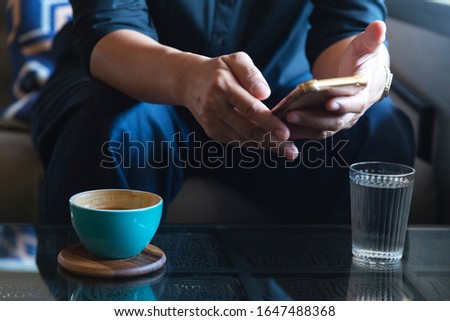 businessman using smartphone to read investment news and reply email to confirm meeting in coffee shop. man drinking latte coffee before going to work on monday morning. vintage photo and film style
