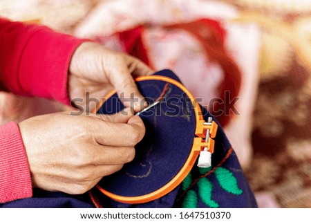 Asian woman's hand is embroidered with tribal native fabric. Sewing pattern. Embroidery in the embroidery frame.