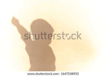 Silhouette shadow of an Asian boy on a white concrete wall.