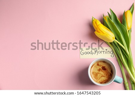 Delicious coffee, beautiful flowers and card with GOOD MORNING wish on pink background, flat lay. Space for text