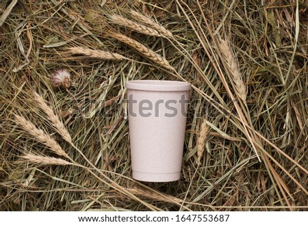 A Reusable cup of straw lies on a hay texture next to the spikelets. the concept of naturalism and minimalism in the trend of zero waste