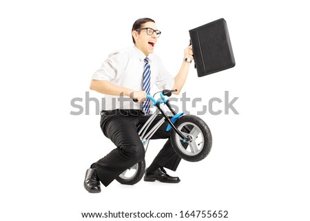 Excited young businessman with leather suitcase riding a small bicycle isolated against white background