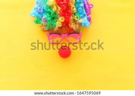 carnival, party and Purim celebration concept (jewish carnival holiday) with clown wig, glasses and red nose over yellow background