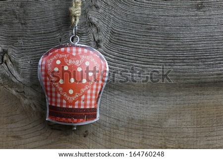 Christmas handmade decoration gingham heart pattern on tin bell over rustic Elm wood background - retro style design, copy space