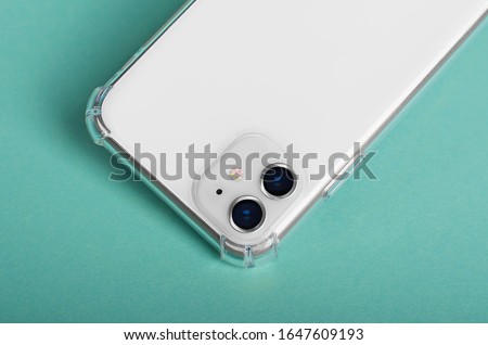 White iPhone 11 close up in clear silicone case back view isolated on green background, phone case mock up iPhone 12