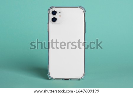 White iPhone 11 in clear silicone case back view isolated on green background, phone case mock up iPhone 12 Royalty-Free Stock Photo #1647609199