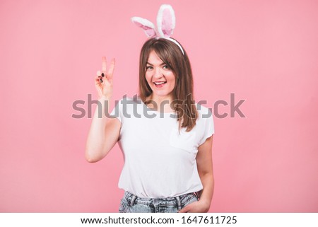 Happy Easter. Portrait of a pretty lovely girl wearing bunny ears standing isolated over pink background. Emotions. Easter concept