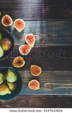 Top view of a bunch of figs on a wooden board, hard light, retro filter appied.
