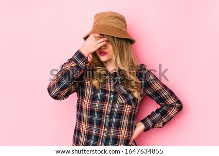 Young caucasian woman wearing a hat isolated having a head ache, touching front of the face.
