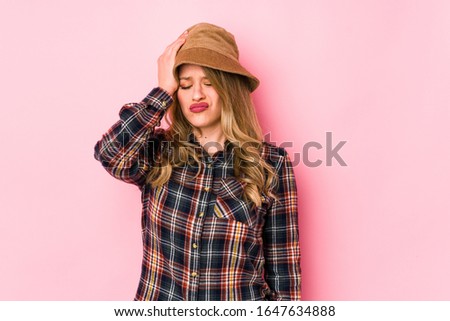 Young caucasian woman wearing a hat isolated tired and very sleepy keeping hand on head.