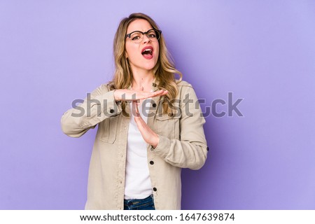 Young caucasian woman isolated on purple background showing a timeout gesture.