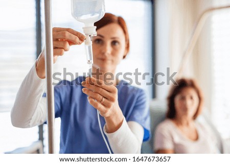 A nurse with IV drip and patient in bed in hospital room. Royalty-Free Stock Photo #1647673657