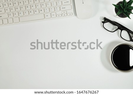 Flat lay, White office desk table. View from above with keyboard, computer mouse, plant potted, succulents, eyeglasses and cup of black coffee. Top view with copy space. Business concept.
