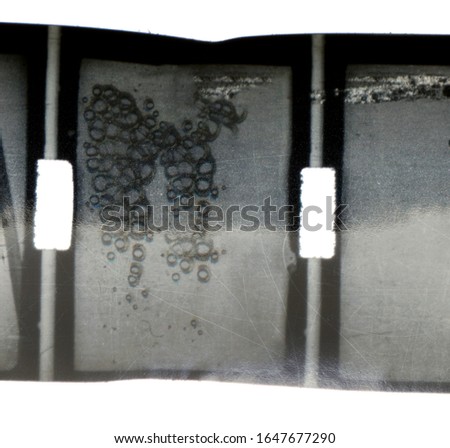 real macro photo of 9,5mm filmstrip with empty frame and burn blister and scratch marks isolated on white background.