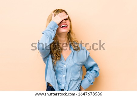 Young blonde caucasian woman laughs joyfully keeping hands on head. Happiness concept.