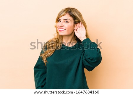 Young blonde caucasian woman trying to listening a gossip.