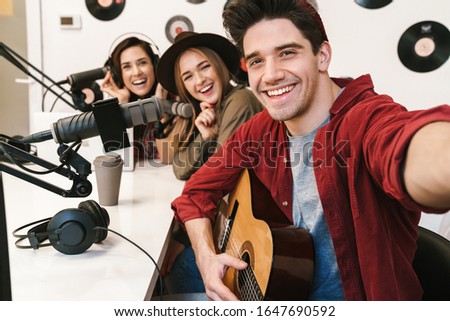 Image of young happy caucasian people performing at radio program while making podcast recording for online show