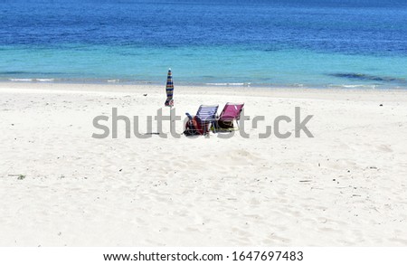 Beach chairs and umbrella on a beach with white sand and turquoise water. Spain.