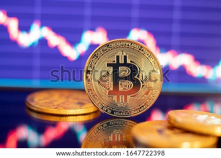 Gold Bitcoin crypto currency on background of red candles chart diagram dawn.