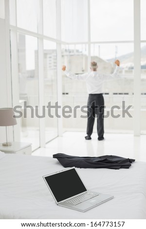 Full length of a businessman looking through window at a hotel bedroom