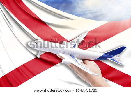 Airplane in hand with national flag State of Alabama on a background of blue sky with sunbeams