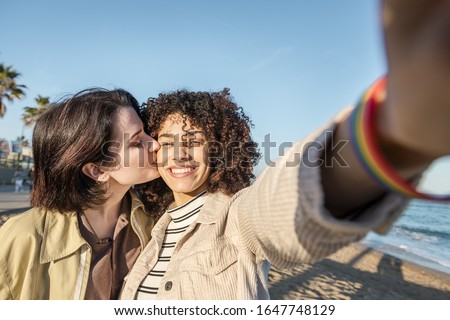 selfie photo of young multiracial couple of beautiful lovely girls smiling and kissing, concept of female friendship and racial diversity