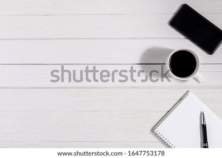 Flat lay, top view wooden office desk. Workspace with smartphone, notebook, pen, coffee cup office supplies with coppy space on white wood table background