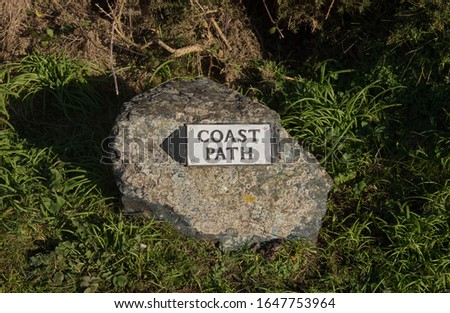 Sign Post and Way Marker for the South West Coast Path Attached to a Granite Stone on the Lizard Peninsula in Rural Cornwall, England, UK