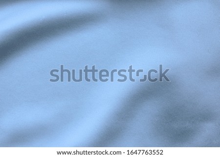 Silky blue sheet material, empty fabric texture wrinkled pattern. Crumpled cloth surface, bluish white background mockup, close up top view 