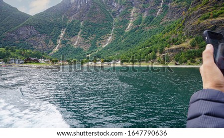 A ferry traveler takes pictures of the shore of the Sogne Fjord, the longest fjord in the world.Scenic view of the surrounding shipping Norwegian fjords.