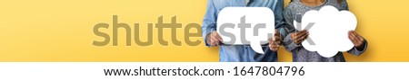 Couple holding white Speech Bubbles on yellow or orange isolated background. Banner, panoramic view for web. Royalty-Free Stock Photo #1647804796