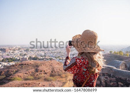 Portrait of young woman play telephone against view of Jodhpur the blue city in Rajasthan India