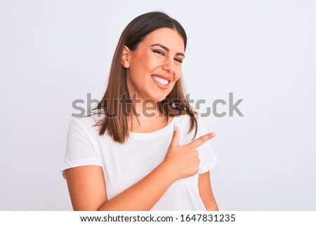 Portrait of beautiful and young brunette woman standing over isolated white background cheerful with a smile of face pointing with hand and finger up to the side with happy and natural expression