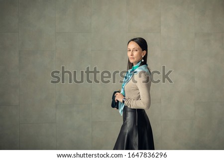 Young 35-40 years old girl Manager of a large company, presentable appearance in office style clothing, with a scarf around her neck, a handbag in her hands. Office and business concept.