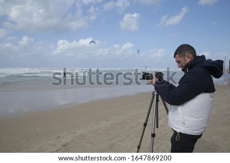 photographer or videographer takes pictures or shoots kite surfers with a digital camera on the beach and sea