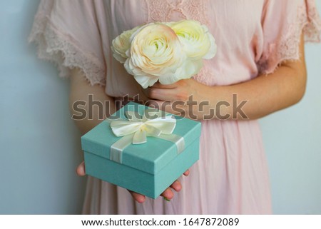 
woman holds in her hands a bouquet of 
ranunculus flowers and gift box, greeting card for wedding, international women's day