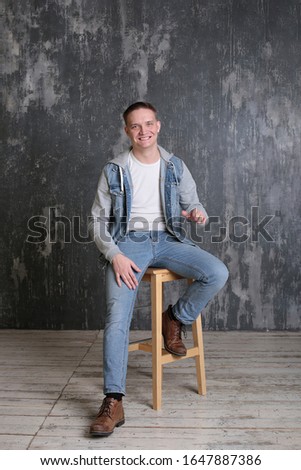 Strong cool emotional guy in denim casual clothes on gray background