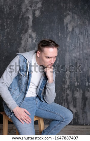 Strong cool emotional guy in denim casual clothes on gray background