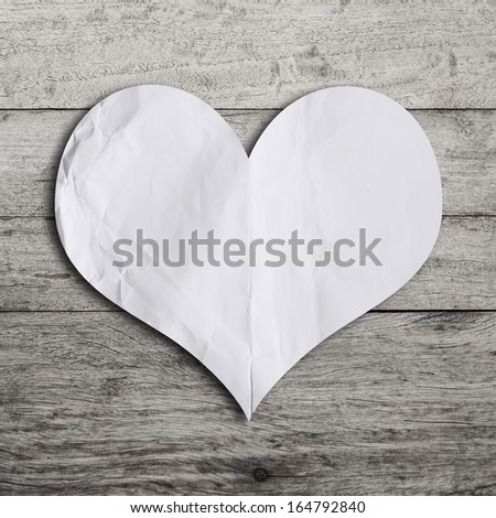 White blank paper note with heart shape on grunge wooden background with copy space 