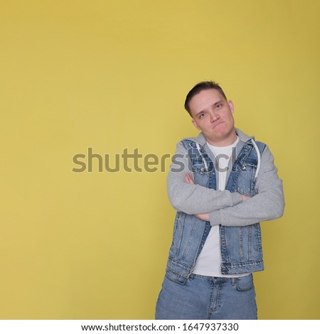 portrait of a tough emotional guy in denim casual clothes on bright yellow background