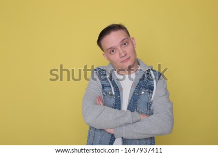 portrait of a tough emotional guy in denim casual clothes on bright yellow background