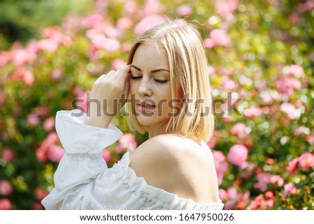girl in a white dress in the garden with pink roses