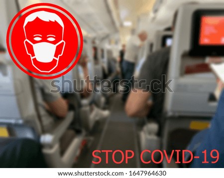 Stop COVID-19. Warning medical protection mask sign on airplane salon at one of the European airports background.