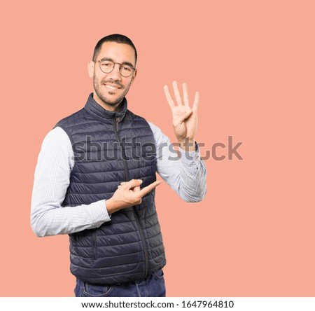 Young man making a number four gesture