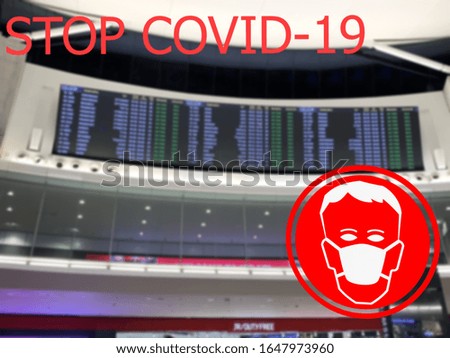 Stop COVID-19. Warning medical protection mask sign on airport flight schedule background.