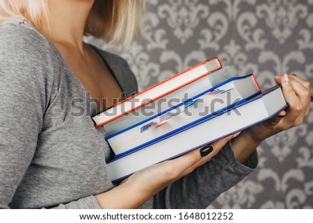 blonde girl holds textbooks, books in her hands, student, schoolgirl, close-up, cropped photo