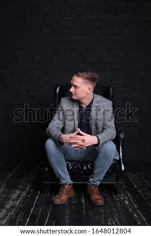 portrait emotional stylish young man in a jacket and shirt on a dark background